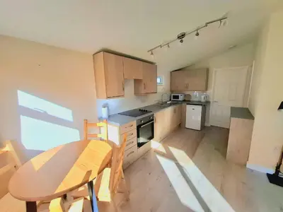 a kitchen with a wooden table and a table and chairs at Cosy Corner Cabin in St Merryn