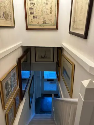 a stairway with paintings and pictures on the walls at Trewetha Cottage Bed & Breakfast in Port Isaac