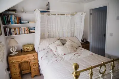a bedroom with a canopy bed and a book shelf at Trewetha Cottage Bed & Breakfast in Port Isaac