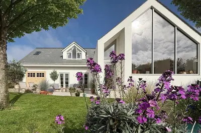 a house with purple flowers in the yard at SeaNest and cabin, walk to beach in St. Agnes