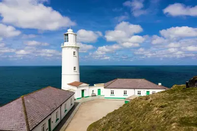 a white lighthouse on a hill next to the ocean at 3 Bed in Constantine Bay oc-t34218 in St Merryn