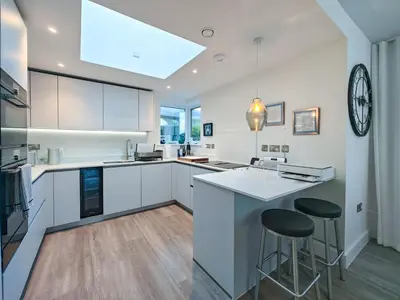 a kitchen with white cabinets and bar stools at 3 Bed in Constantine Bay oc-t34218 in St Merryn