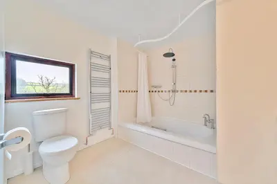 a white bathroom with a toilet and a bath tub at 4 Bed in Tresarrett oc-b34254 in Blisland