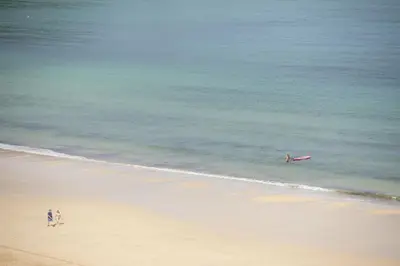 a person in the ocean with a surfboard in the water at Emerald - Stunning Views - Free Parking and WiFi - Coffee Machine in Carbis Bay