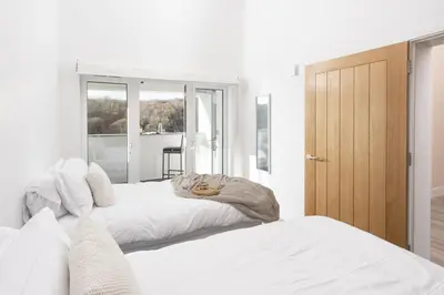 two white beds in a room with a door at Redshank-Pets Allowed-River View-Cinema Room-Free Parking & WiFi in Looe