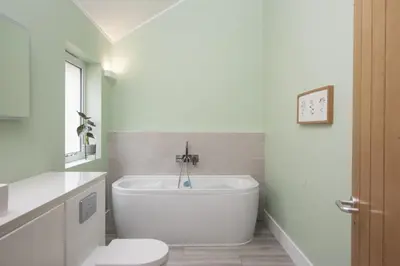 a white bathroom with a tub and a toilet at Redshank-Pets Allowed-River View-Cinema Room-Free Parking & WiFi in Looe