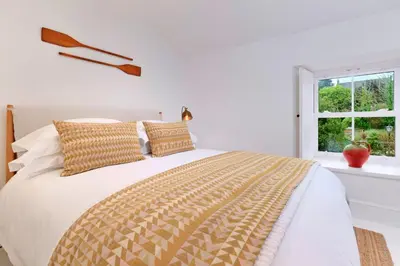 a white bedroom with a large bed and a window at Finest Retreats - Mill Stone Cottage in Nancledra