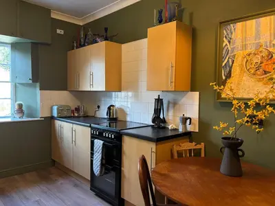 a kitchen with a table and a stove top oven at Church View, Helston Old Town in Helston