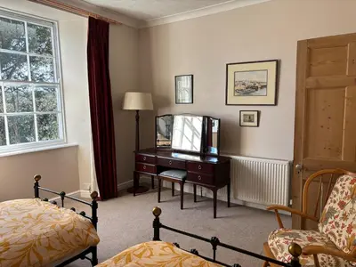 a bedroom with a desk with a mirror and a bed at Church View, Helston Old Town in Helston