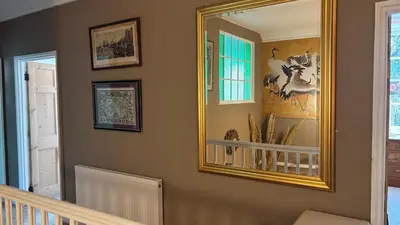 a mirror on a wall in a room with a staircase at Church View, Helston Old Town in Helston
