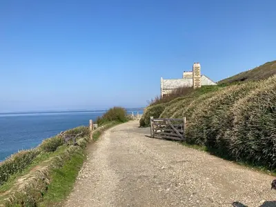 a dirt road with a house on a hill next to the ocean at Church View, Helston Old Town in Helston