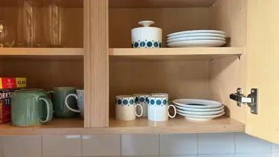 a kitchen shelf with cups and plates and bowls at Church View, Helston Old Town in Helston