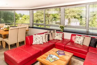 a living room with a red couch and a table at Atlantic House En-Suite Bedrooms 5 mins to Beach and Shops in St. Agnes