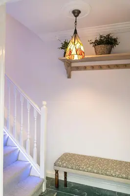 a stairway with a bench and a chandelier at 90A Tower Road in Newquay
