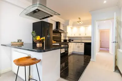 a kitchen with white cabinets and a black counter top at 90A Tower Road in Newquay