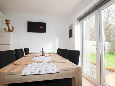 a dining room table with chairs and a large window at Poldam in St Austell