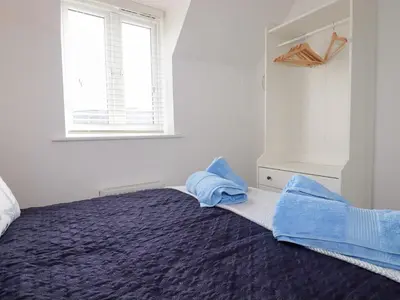 a bedroom with a bed with blue sheets and a window at Poldam in St Austell