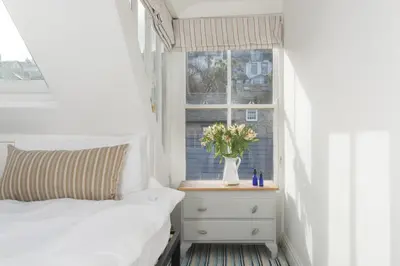 a bedroom with a bed and a window with a vase of flowers at Walters on The Digey - 100m to beach - pets allowed in St Ives