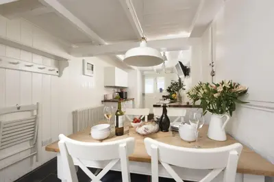 a dining room with a wooden table and white chairs at Walters on The Digey - 100m to beach - pets allowed in St Ives