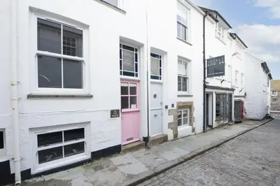 a white building with a pink door on a street at Walters on The Digey - 100m to beach - pets allowed in St Ives
