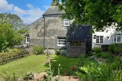 a stone house with a garden in front of it at Cottage - Sleeps 2 - River Lynher walks & fishing in Linkinhorne