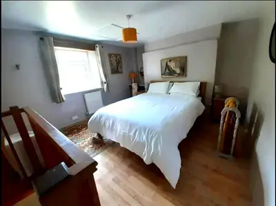 a bedroom with a large white bed and a window at Cottage - Sleeps 2 - River Lynher walks & fishing in Linkinhorne
