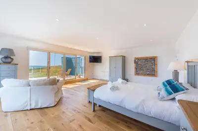 a living room with two white couches and the ocean at Cornwall Holiday Home with Hot Tub & Sea views in St Merryn