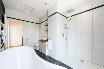 a white bathroom with a shower and a tub at Cornwall Holiday Home with Hot Tub & Sea views in St Merryn