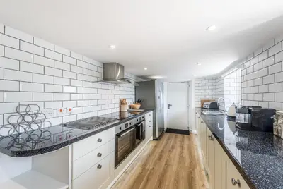 a kitchen with white appliances and black counter tops at Cornwall Holiday Home with Hot Tub & Sea views in St Merryn
