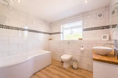 a bathroom with a tub and a toilet and a sink at Cornwall Holiday Home with Hot Tub & Sea views in St Merryn