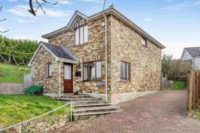 a brick house with a green bench in front of it at 3 Bed in Polruan oc-l35010 in Fowey