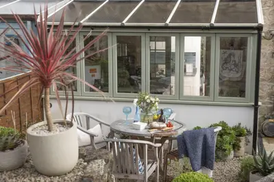 a patio with a table and some plants and a house at 1 The Cottages - Family friendly, Parking, Woodburner in Penzance
