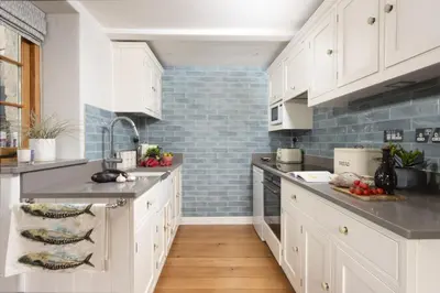a kitchen with white cabinets and blue tiles at 1 The Cottages - Family friendly, Parking, Woodburner in Penzance