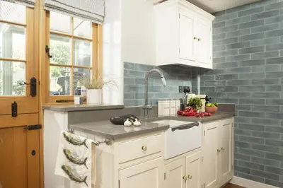 a kitchen with white cabinets and blue tiles at 1 The Cottages - Family friendly, Parking, Woodburner in Penzance