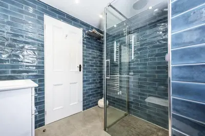 a bathroom with a glass shower with blue tiles at 1 The Cottages - Family friendly, Parking, Woodburner in Penzance