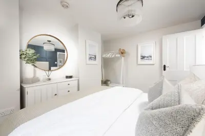 a white bedroom with a bed and a mirror at 1 The Cottages - Family friendly, Parking, Woodburner in Penzance