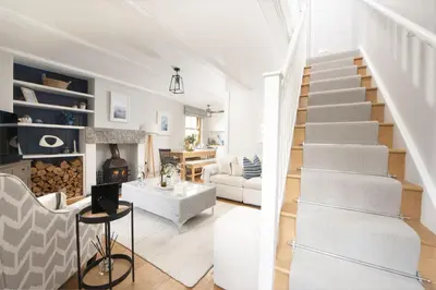 a white living room with stairs and a fireplace at 1 The Cottages - Family friendly, Parking, Woodburner in Penzance