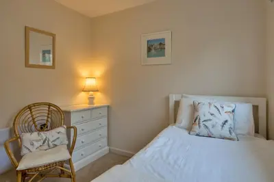 a bedroom with a bed and a chair and a dresser at Finest Retreats - Smugglers Loft at Mixtow Creek in Lanteglos