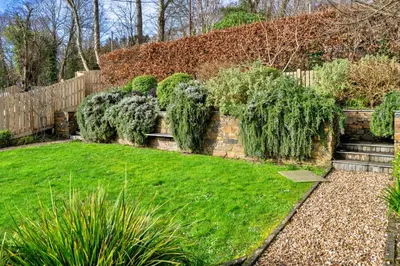 a garden with a retaining wall and green grass at Finest Retreats - Smugglers Loft at Mixtow Creek in Lanteglos