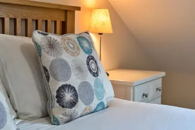 a pillow sitting on top of a bed with a lamp at Finest Retreats - Smugglers Loft at Mixtow Creek in Lanteglos