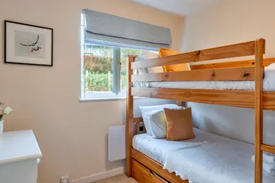 a bedroom with two bunk beds and a window at Finest Retreats - Bosuns Loft at Mixtow Creek in Lanteglos