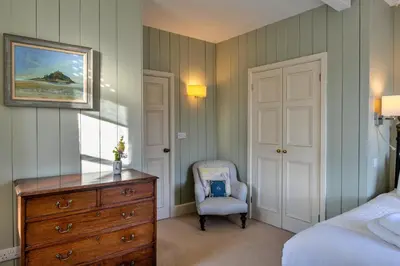 a bedroom with a dresser and a bed and a chair at Finest Retreats - Captains Cottage at Mixtow Creek in Lanteglos