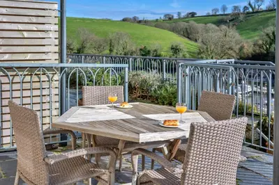 a wooden table with two glasses of orange juice at Finest Retreats - Captains Cottage at Mixtow Creek in Lanteglos