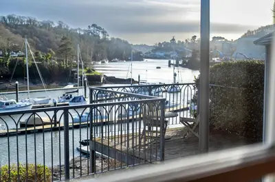 a balcony with a view of a marina with boats at Finest Retreats - Captains Cottage at Mixtow Creek in Lanteglos