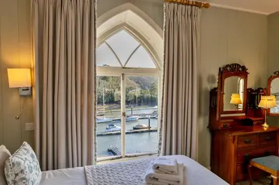 a bedroom with a window with a view of a boat at Finest Retreats - Captains Cottage at Mixtow Creek in Lanteglos
