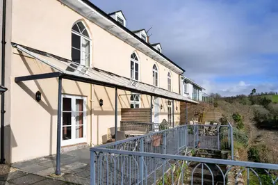 an external view of a house with a balcony at Finest Retreats - Captains Cottage at Mixtow Creek in Lanteglos