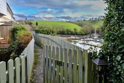 a fence next to a river with a boat in it at Finest Retreats - Kits House at Mixtow Creek in Lanteglos