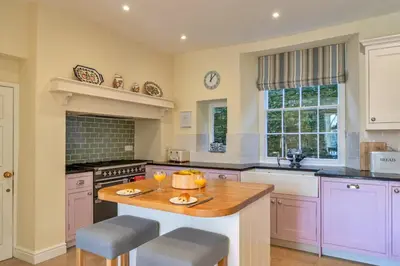 a kitchen with purple cabinets and a island with two stools at Finest Retreats - Kits House at Mixtow Creek in Lanteglos