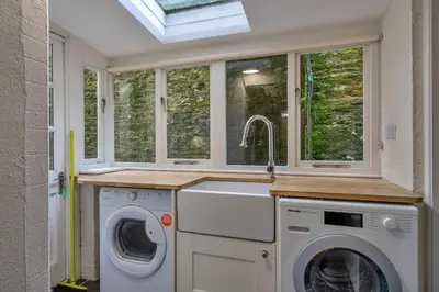a laundry room with a sink and washing machines at Finest Retreats - Kits House at Mixtow Creek in Lanteglos