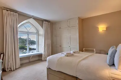 a bedroom with a large bed and a window at Finest Retreats - Kits House at Mixtow Creek in Lanteglos